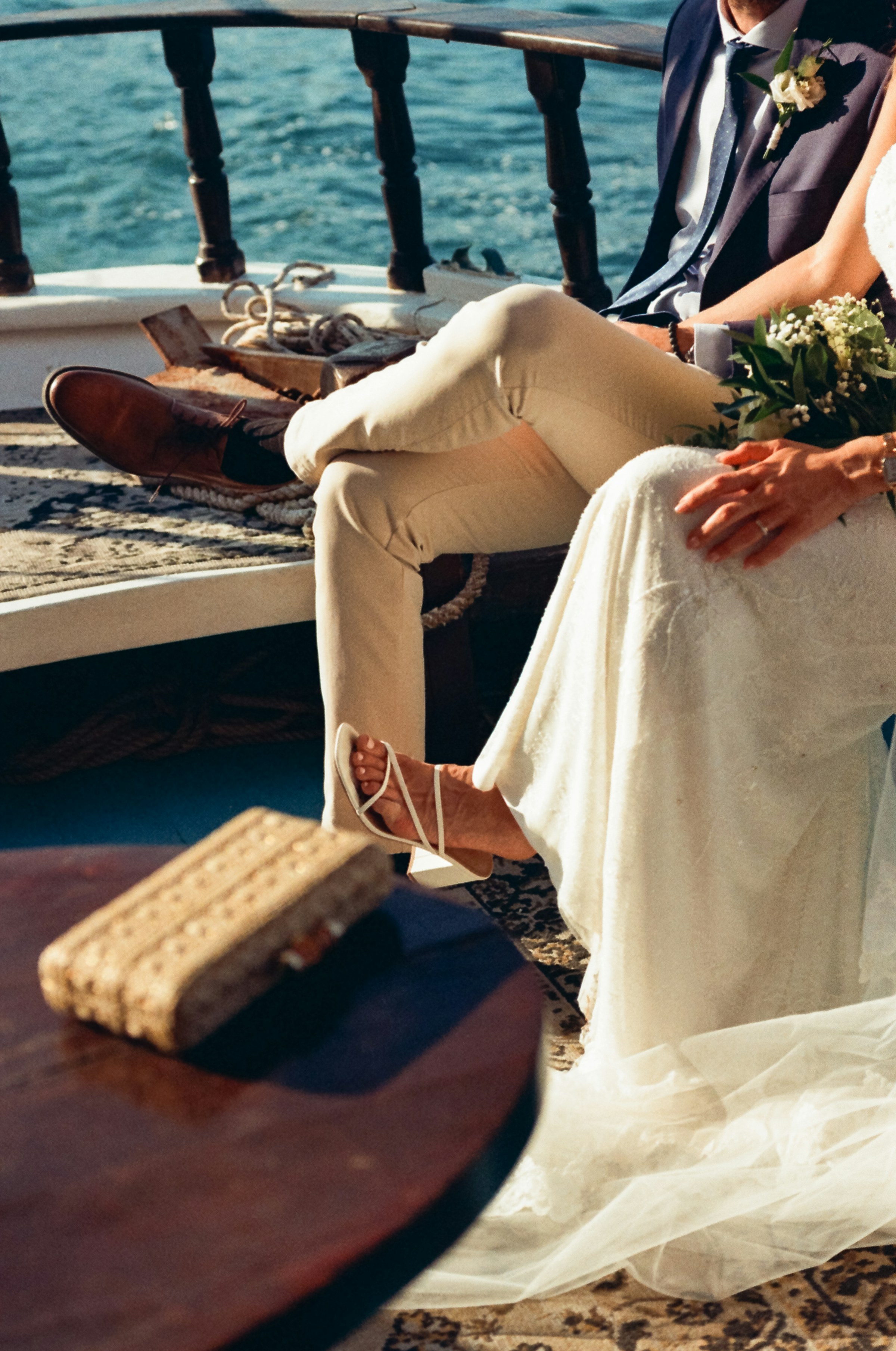 A bride and groom celebrating on a boat deck at sea, with a wedding bouquet